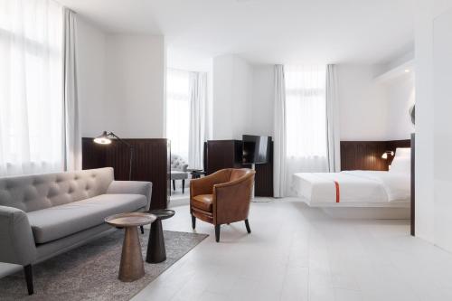 a hotel room with a bed and a couch and a bed at Ruby Hanna Hotel Stuttgart by IHG in Stuttgart