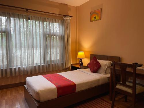 a bedroom with a bed and a lamp and a window at ROKPA Guest House in Kathmandu