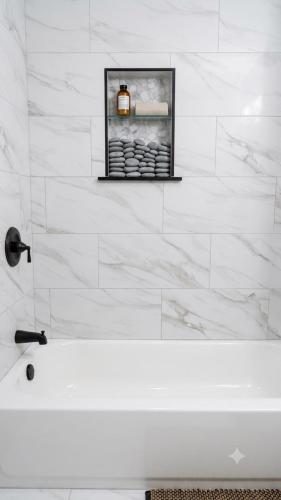 a white bathroom with a tub and a picture on the wall at Stylish Studio in Oleander Close to Downtown in Bakersfield