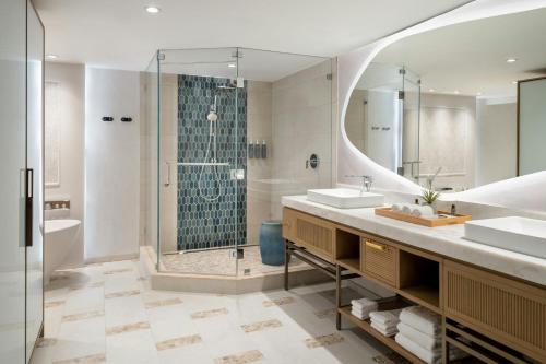 a bathroom with a shower and two sinks and a mirror at The Westin Tampa Bay in Tampa