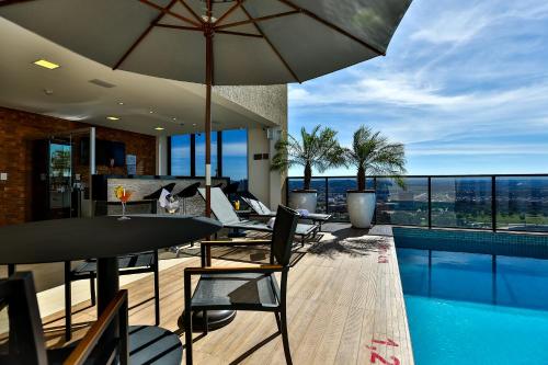 un patio con mesa, sillas y sombrilla en Quality Hotel Flamboyant en Goiânia