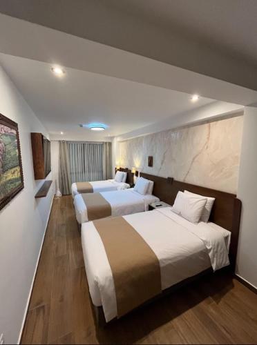 a hotel room with three beds in it at Alpacaterra Machupichu Hotel in Machu Picchu
