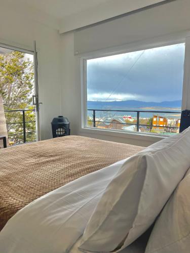 a bedroom with a bed and a large window at Balcón Austral beautiful apartment with incredible views of the mountains and the city in Ushuaia