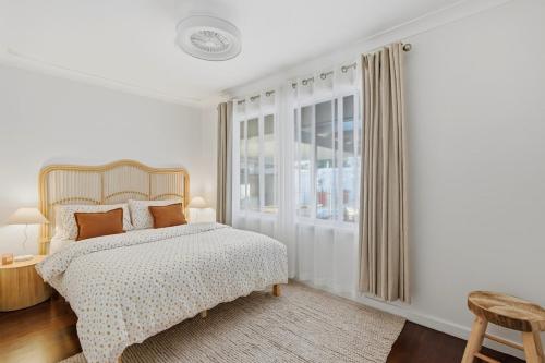 a white bedroom with a bed and a window at Mediterranean Beachside retreat with a pool in Broadwater