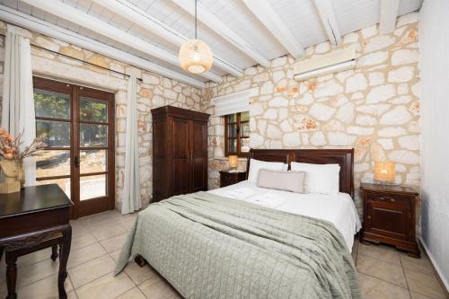 a bedroom with a bed and a desk and a stone wall at Villa Boscheto Tria in Agios Leon