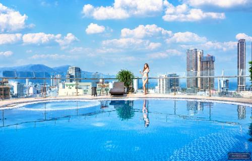 a woman standing on the roof of a building with a pool at Merry Land Hotel Da Nang in Danang