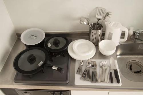 a kitchen counter with a sink with plates and utensils at SCREEN Shibamata 20 mins to Skytree in Tokyo