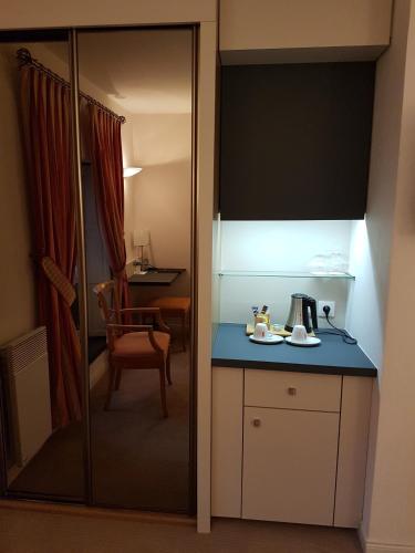 a small kitchen with a blue counter and a room at Hotel Restaurant Le Dauphin et Le Spa du Prieuré in Caen