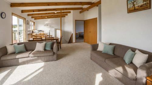 a living room with two couches and a table at Summer House On Kurrawa - stunning beach views in Kioloa
