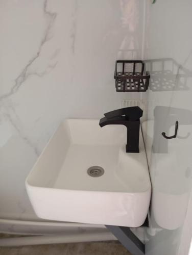 a white bathroom sink with a black faucet at ИНХаус Т in Cholpon-Ata