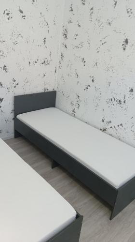 two white beds in a room with a wall at ИНХаус Т in Cholpon-Ata