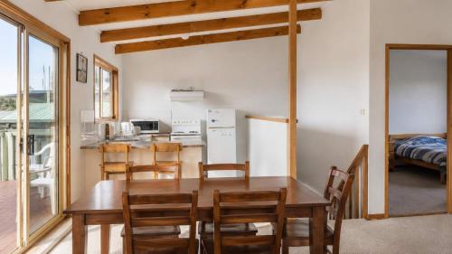 a kitchen and dining room with a wooden table and chairs at Summer House On Kurrawa - stunning beach views in Kioloa