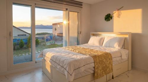 a bedroom with a bed and a large window at That Day's Namhae Ocean View Pension in Namhae