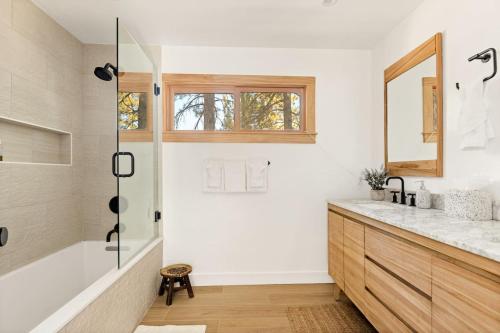 a bathroom with a tub and a sink and a mirror at Lakefront View Stunner in Big Bear Lake