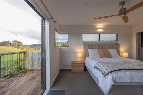 a bedroom with a bed and a balcony at Tahana Villa - River View Retreat - 3 Bedroom in Oakura