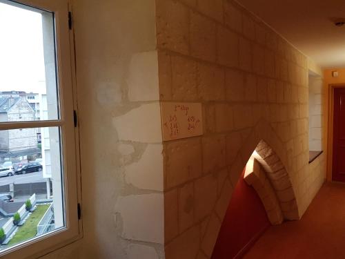a room with a brick wall with a window at Hotel Restaurant Le Dauphin et Le Spa du Prieuré in Caen