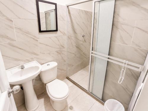 a bathroom with a shower and a toilet and a sink at La Casita Rooms - Habitaciones Coveñas in Coveñas
