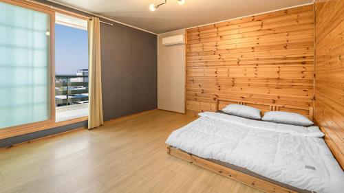 a bedroom with a wooden wall and a bed at Gangneung Basecamp Pension in Gangneung