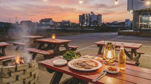 a picnic table with food on it with a fire at Gangneung Basecamp Pension in Gangneung