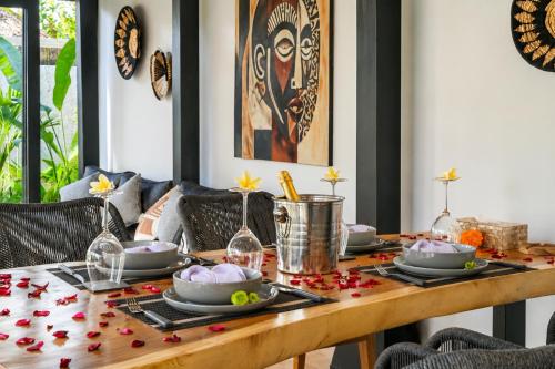 a dining room table with dishes and flowers on it at Villa Jasmine by Anakara in Ubud