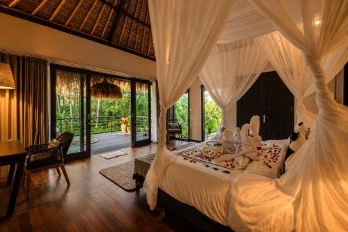 a bedroom with a large bed and a desk and a table at Villa Jasmine by Anakara in Ubud