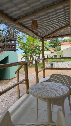 a table and chairs on a porch with a table and a chair at Maré Suítes Maragogi in Maragogi