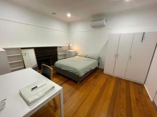 a bedroom with a bed and a desk and a table at Oakleigh South Charm in Oakleigh South