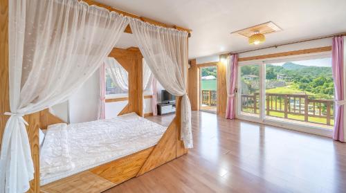 a bedroom with a canopy bed and a large window at Ganghwa Herb Pension in Incheon