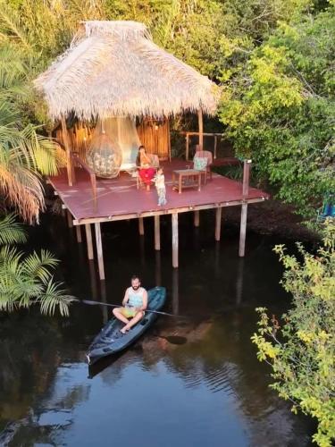 a man on a raft in the water in front of a house at Casa da Arvore Experiencia com cafe da manha e ar condicionado in Santarém