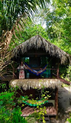 a woman standing in a hut with a thatch roof at Casa da Arvore Experiencia com cafe da manha e ar condicionado in Santarém