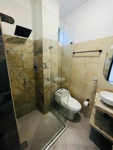 a bathroom with a toilet and a glass shower at BLUE DAYS Hotel Melgar in Melgar