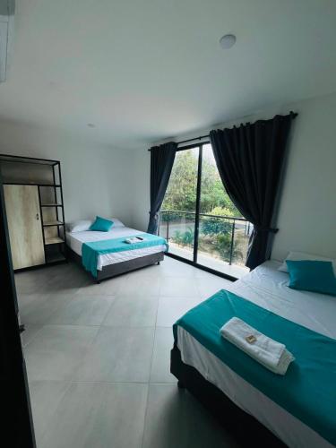 two beds in a room with a large window at BLUE DAYS Hotel Melgar in Melgar