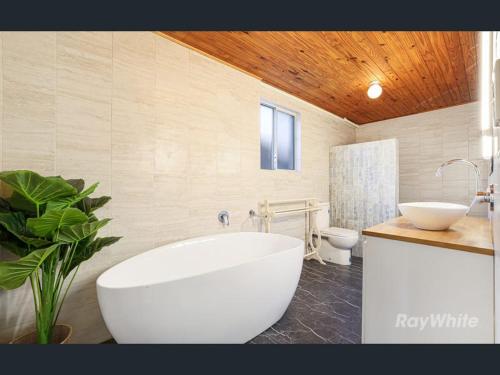 a bathroom with a tub and a sink and a toilet at Driftwood in Bargara