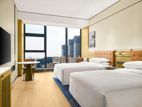 a hotel room with three beds and a large window at Four Points by Sheraton Shanwei Lufeng in Shanwei