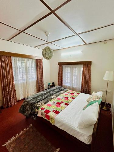 a bedroom with a large bed with a quilt on it at Springdale Villa in Kodaikānāl