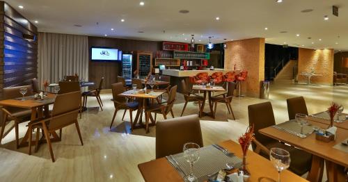 a restaurant with tables and chairs and a bar at Quality Hotel Flamboyant in Goiânia