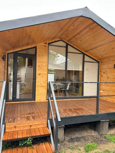 a house with glass windows and a wooden deck at Барнхаус in Cholpon-Ata