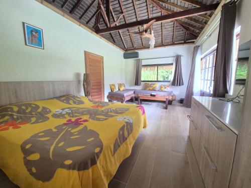a bedroom with a bed with a yellow comforter at Hôtel Atiapiti in Opoa
