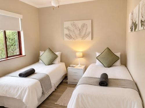 two beds in a bedroom with a lamp and a window at Thyme Inn on Greenway in White River