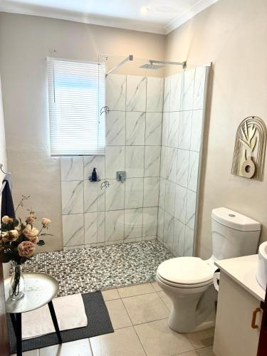 a bathroom with a shower with a toilet and a sink at Thyme Inn on Greenway in White River