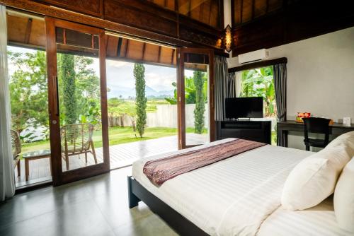 a bedroom with a large bed and a large window at MAHALAYA Garden Resort in Pablengan