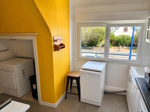 a small kitchen with a yellow wall and a window at An Dorzell beach 60 meters in Cléder