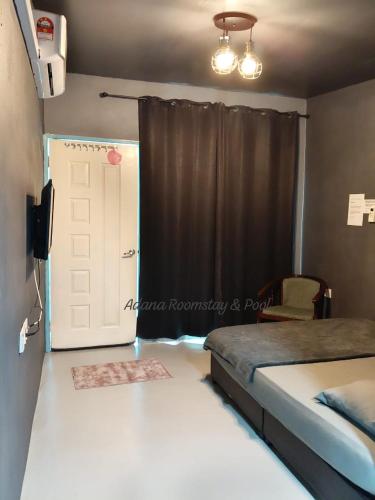 a bedroom with a bed and a door with a window at Adana Homestay & Pool in Kangar
