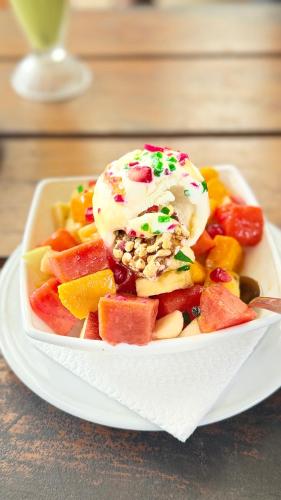 a white plate with a bowl of fruit and ice cream at Ela addara Home stay in Lukasgoda
