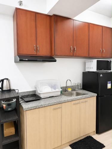 a kitchen with wooden cabinets and a black refrigerator at Bacolod Condo CASA LEA in Bacolod