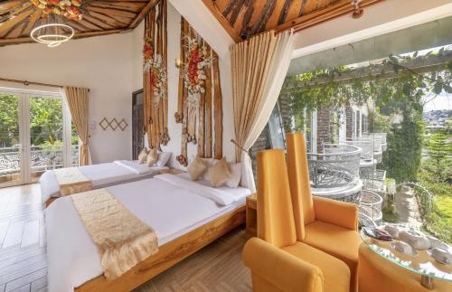a bedroom with a bed and a chair and a window at Mac Valley DaLat Hotel in Da Lat