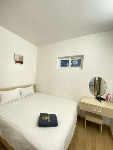 a white bedroom with a bed and a mirror at Da nang seaview MT apartment in Danang