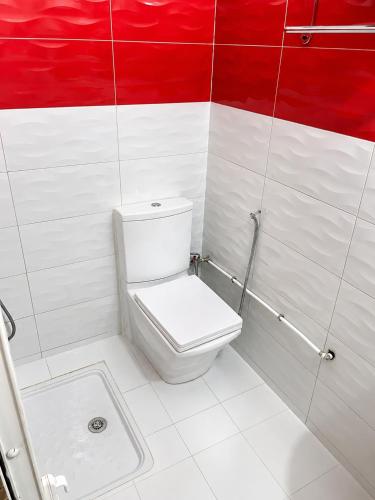 a bathroom with a toilet and a red and white wall at Perfect home in Temara
