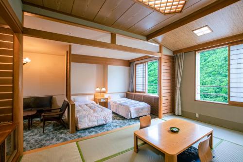 a room with a bed and a desk and a table at Choyo Tei in Kamikawa