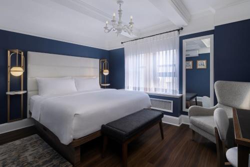 a bedroom with a large white bed and a chair at voco The Franklin New York by IHG in New York